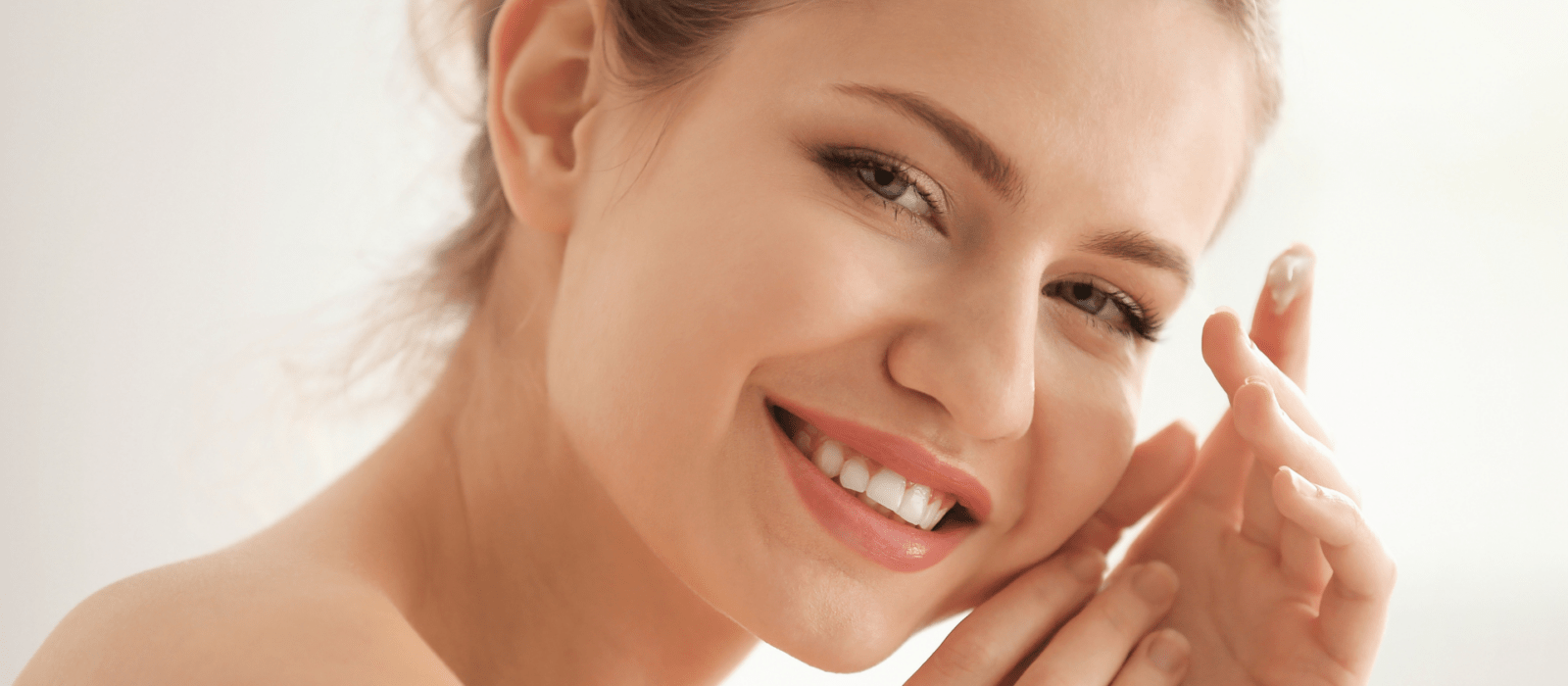 A woman's portrait looking at the camera with skin care product on her finger.